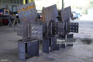 Steel structures, metalwork, and welding. Large steel components in an industrial workshop. Structural steel with welded joints and bolt holes.
