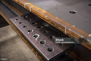 Steel plate with machined bolt holes showing grind marks as part of the fabrication process.